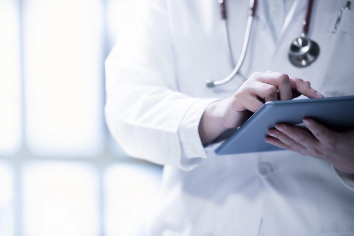 Photo of doctor with tablet illustrates blog: "Medical Legal Billing in California: Bill Proposes Change to Independent Bill Review (IBR) Fees"