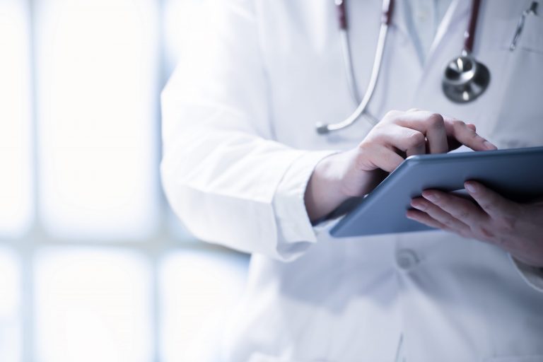 Photo of doctor with tablet illustrates blog: "Medical Legal Billing in California: Bill Proposes Change to Independent Bill Review (IBR) Fees"