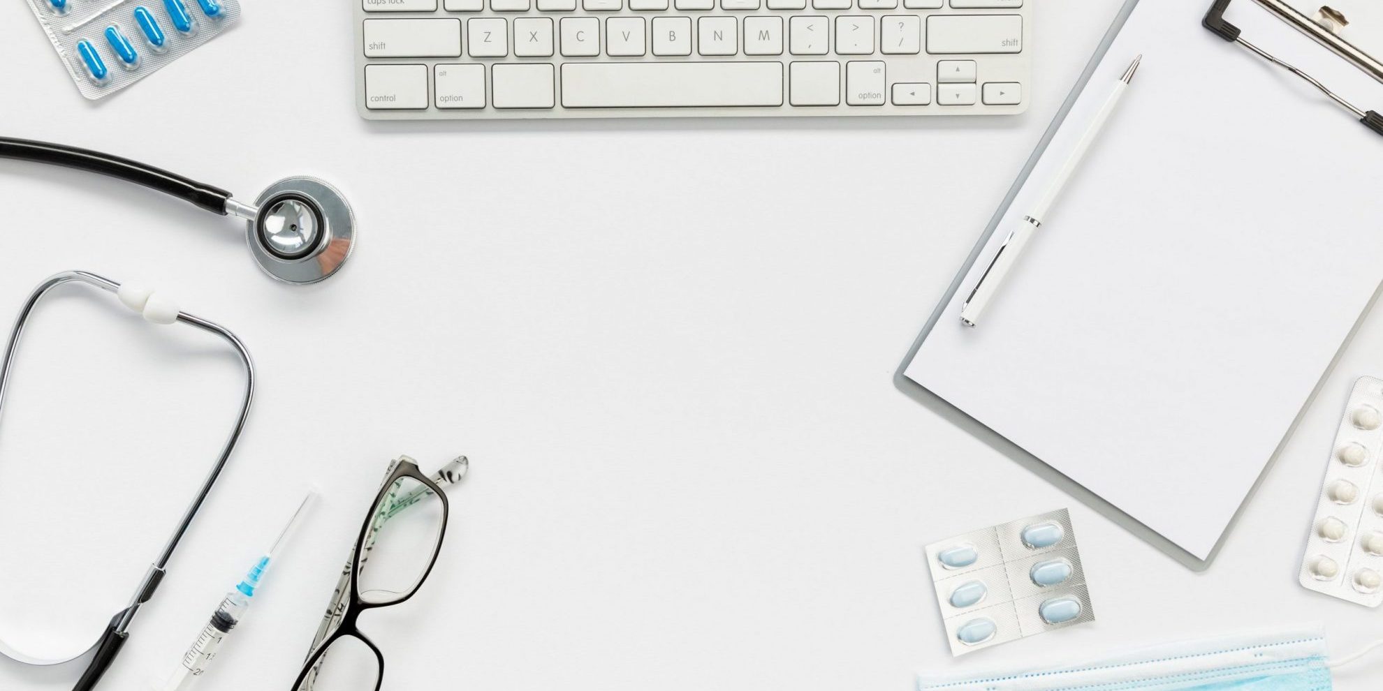 Photo of desk with keyboard, stethoscope, and facemask, among other items, illustrates blog "California’s DWC Is Accepting Applications for QMEs"
