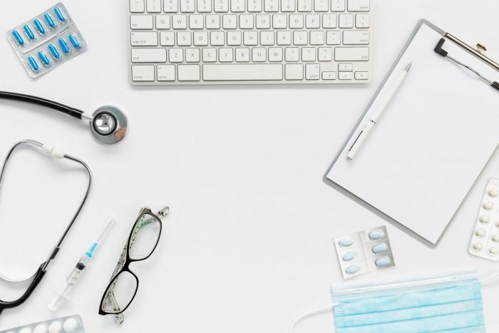 DoctorDesk Photo of desk with keyboard, stethoscope, and facemask, among other items, illustrates blog "California’s DWC Is Accepting Applications for QMEs"