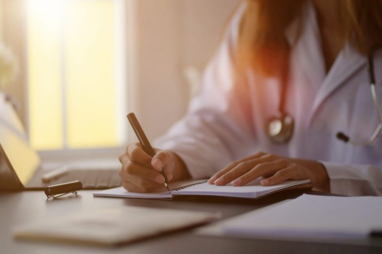 Photo of doctor writing illustrates blog: "Medical Legal Billing in California: What Is a QME Doctor Deposition?"