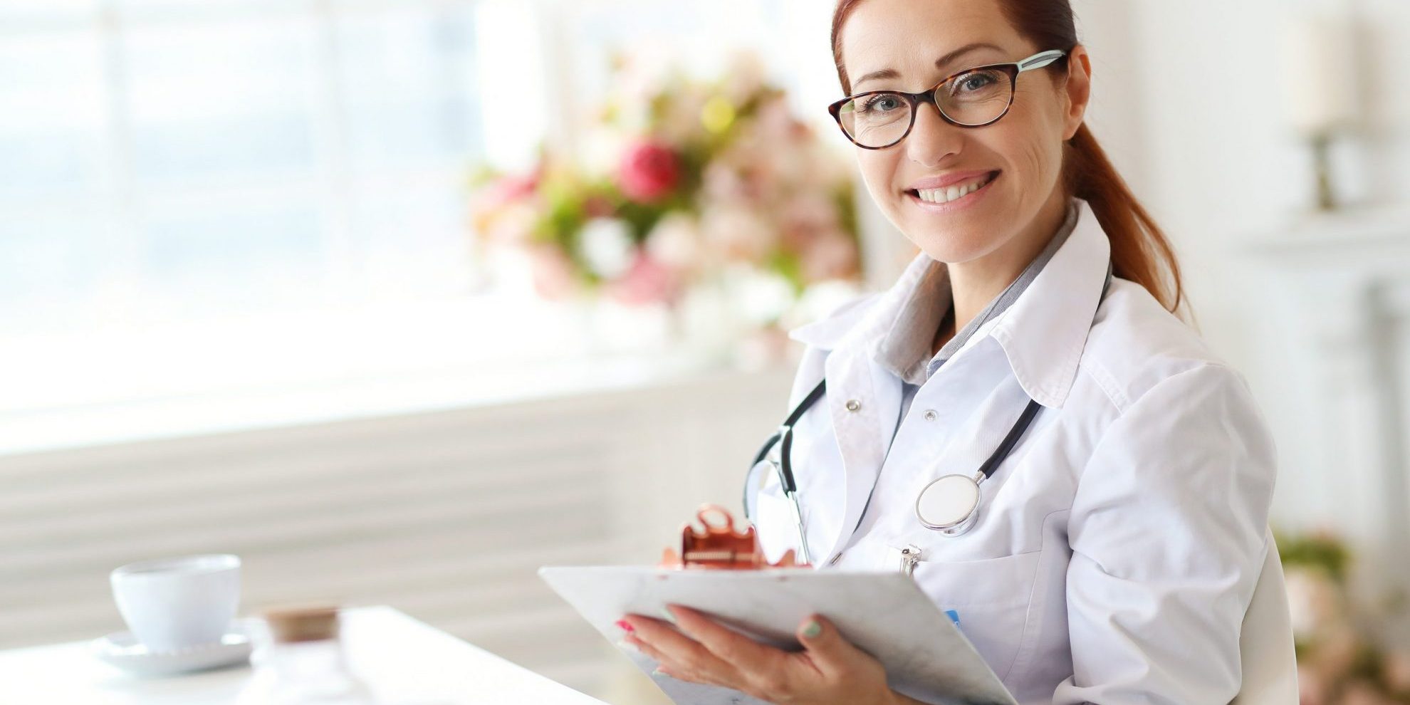 Photo of a smiling female doctor holding a clipboard illustrates blog: "How To Become a Qualified Medical Evaluator (QME) in California?"