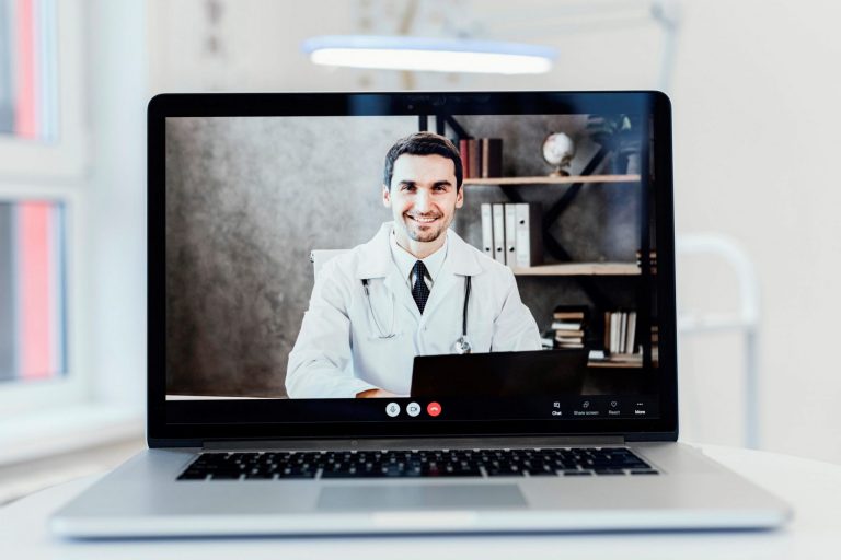 Photo of doctor on laptop screen illustrates blog: "It’s Official: the DWC Extends Emergency Regulations for Medical-Legal Evaluations"