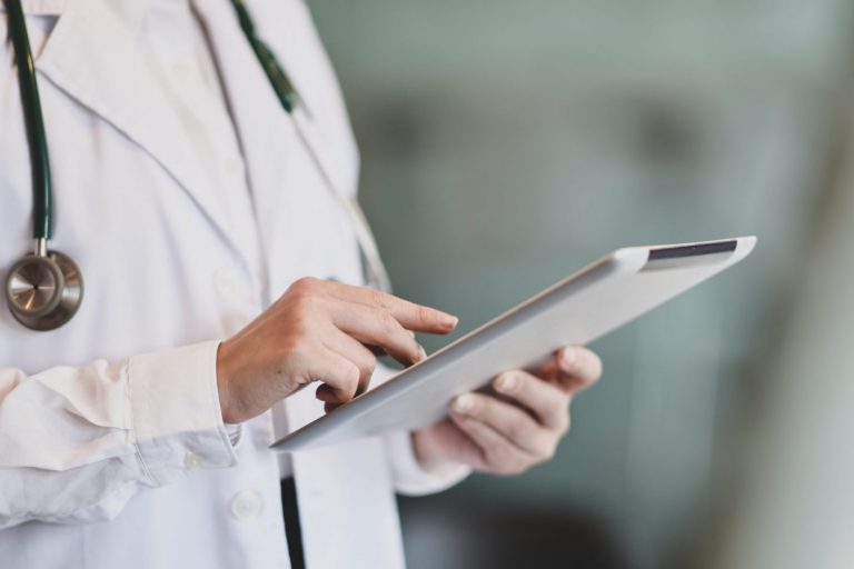 Photo of doctor holding tablet illustrates blog: "California Workers’ Comp Glossary"