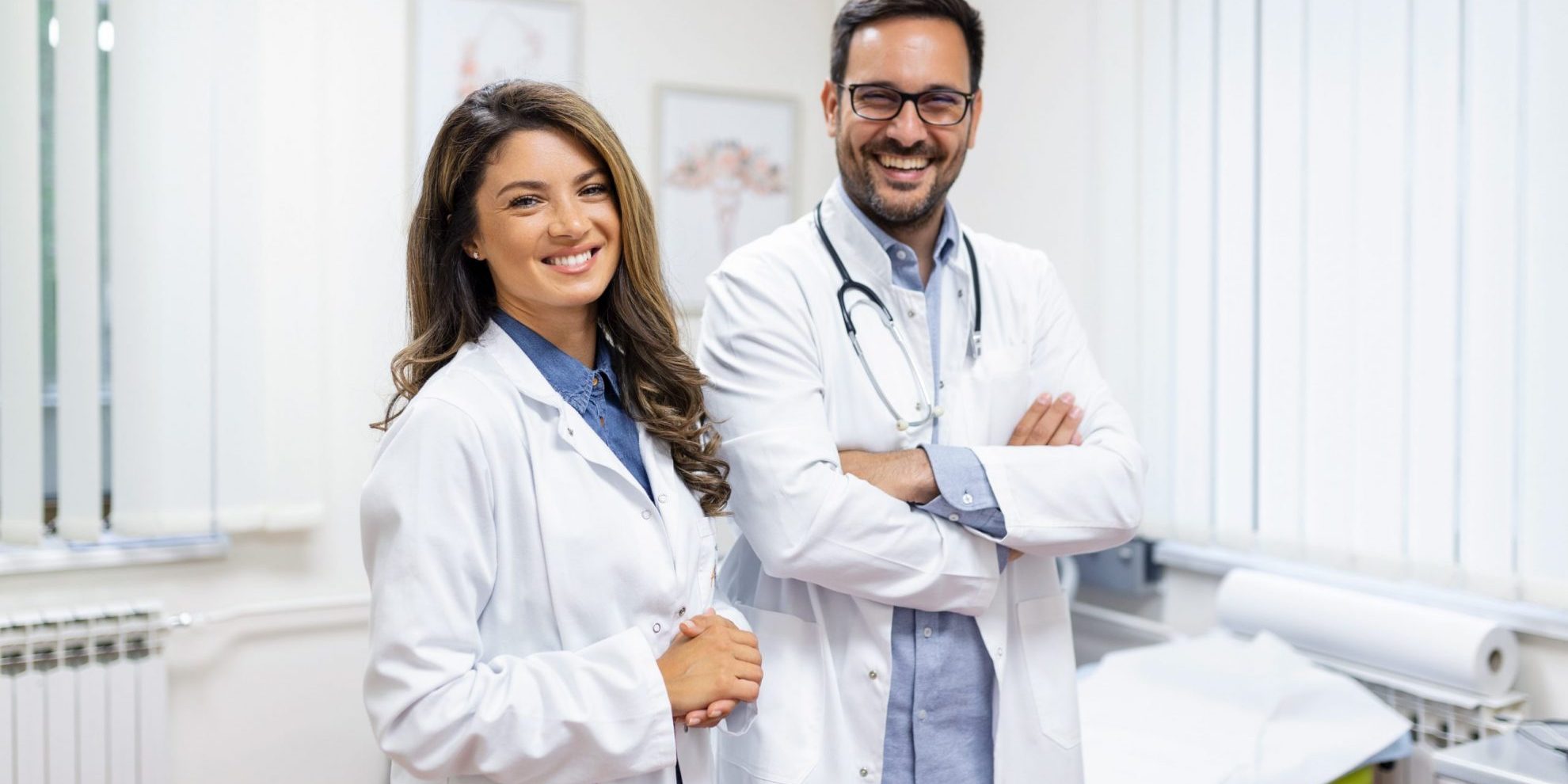 Photo of two smiling doctors illustrates blog: "California’s DWC Studies Proposal To Increase Time To Schedule Medical-Legal Evaluations"