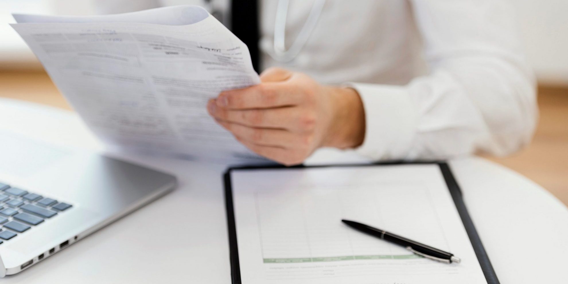 Closeup of man in lab coat with clipboard in front of him illustrates blog "5 Medical Practice Management Tips to Help You Succeed"