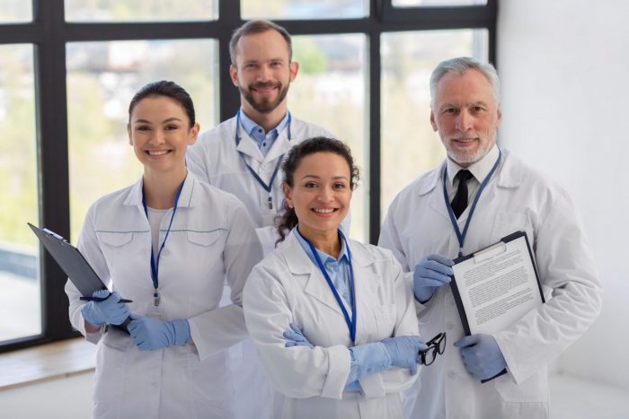 MedicalPracticeTeam Team of healthcare professionals in lab coats illustrate blog "Here’s How Small Medical Practices Can Optimize their Revenue Cycle"