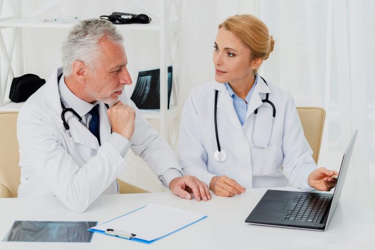 Photo of doctors looking at laptop illustrates blog "How Long Does the QME Exam Take?"