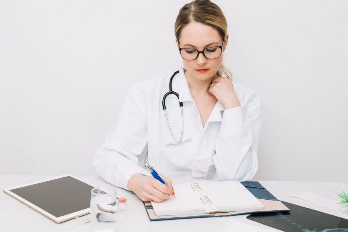 Female doctor writing illustrates blog "What Should I Bring to a QME Examination?"