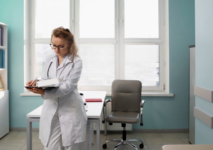 Female physician writing in an office illustrates blog "Medical Legal Evaluations: How Much Time Do I Have To Complete the QME Report?"