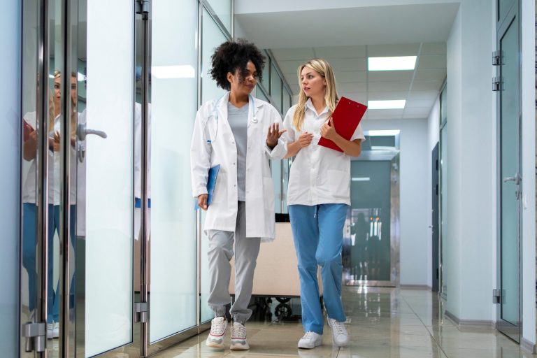 Two female doctors walking side by side illustrate blog "What Is Revenue Cycle Management?"