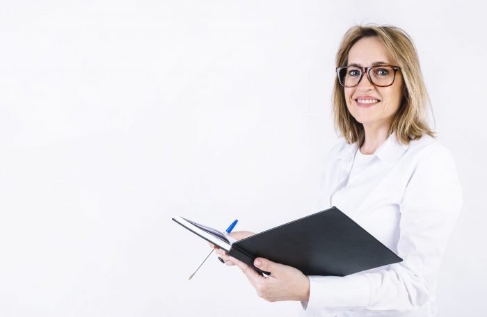 Woman in white lab coat holding open book illustrates blog "Essential Medical Billing Terms You Need To Know"