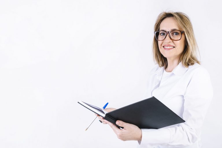Woman in white lab coat holding open book illustrates blog "Essential Medical Billing Terms You Need To Know"