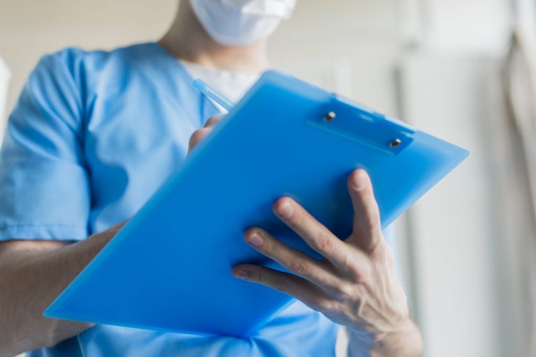 Person in scrubs writing on clipboard illustrates blog "California: Can I Request an Extension To Complete a Medical Legal Report?"