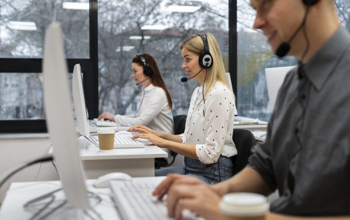 Three people sitting at desks in call center.