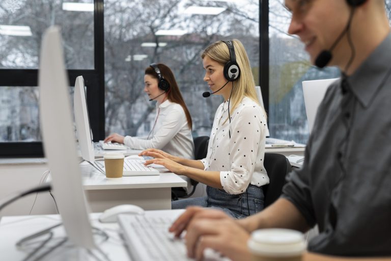 calls-fp Three people sitting at desks in call center.