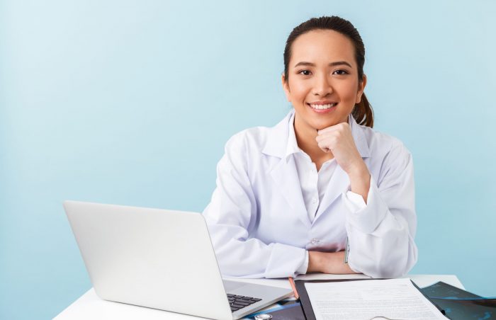 Smling woman behind desk illustrates blog "What Does a Referral Coordinator Do?"