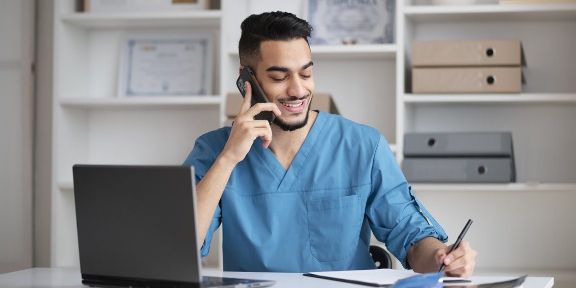 doctor-office-fp Man in scrubs talking on phone illustrates blog "Benefits of an Efficient Healthcare Call Center"