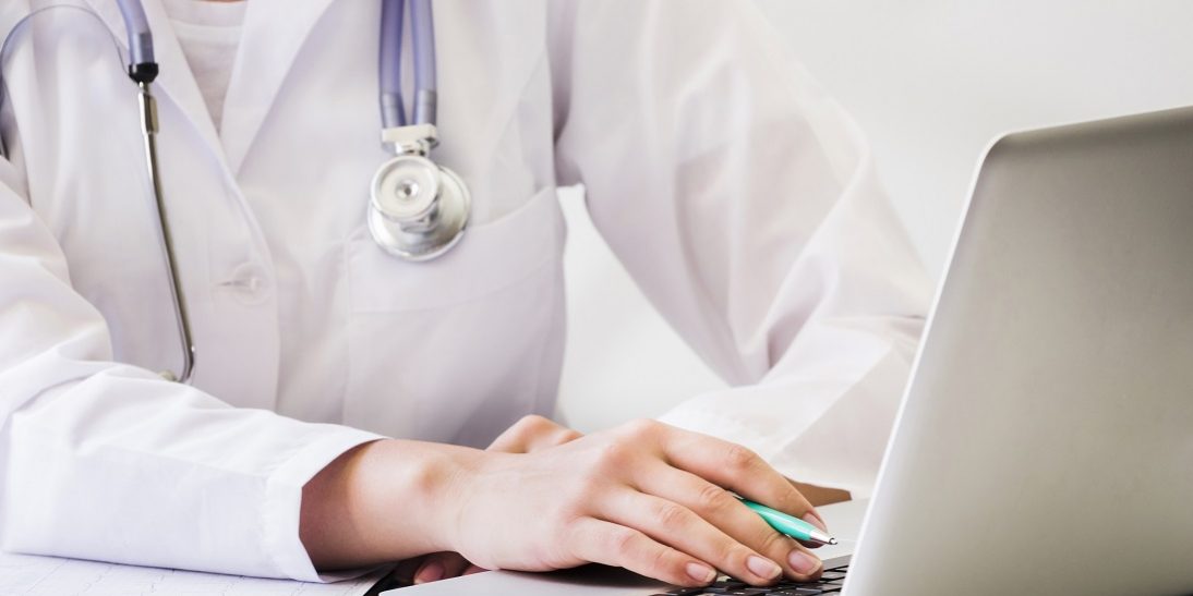 Closeup of female doctor using computer illustrates blog "What Role Does Medical Billing Play in Revenue Cycle Management?"