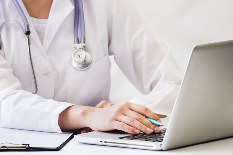 Closeup of female doctor using computer illustrates blog "What Role Does Medical Billing Play in Revenue Cycle Management?"